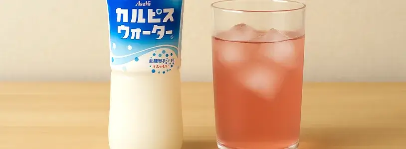 グラスに氷を入れ、赤玉ワインをカルピスウォーターで割ったドリンク。横にはカルピスウォーターのボトルが置かれている写真。