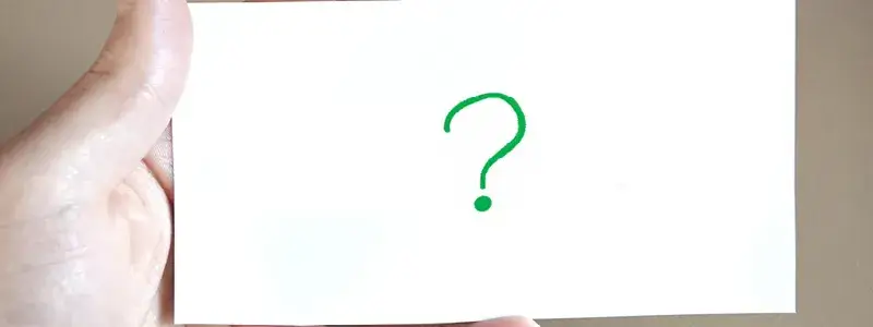 手に持ったカードに描かれた緑のクエスチョンマーク。赤玉ワインがなぜ“ワインじゃない”と言われるのかという疑問を表現。