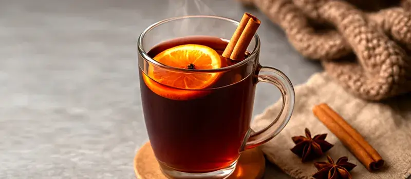 シナモンスティックとスライスオレンジが添えられたホットアップルワインのドリンク。冬にぴったりの温かくスパイシーなアレンジを表現した一枚。