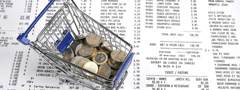 レシートの上に置かれた小さなカートとユーロ硬貨。価格帯や販売場所をイメージした写真