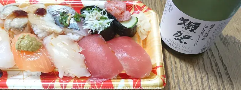 寿司の盛り合わせと純米大吟醸スパークリング「獺祭」のボトル。和食との相性を楽しむシーン。
