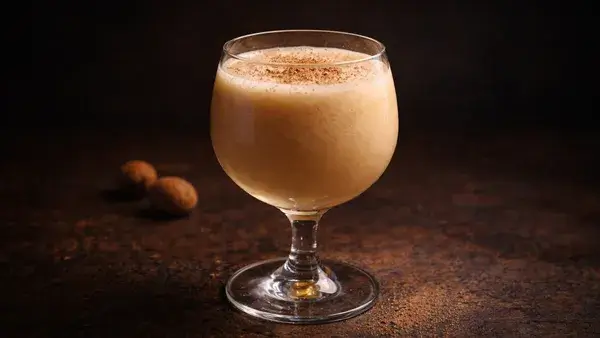 ブランデー・フリップのカクテル。クリーミーな淡いブラウンとナツメグの香りが、秘めた想いや切なさを静かに表現した落ち着いたイメージ画像