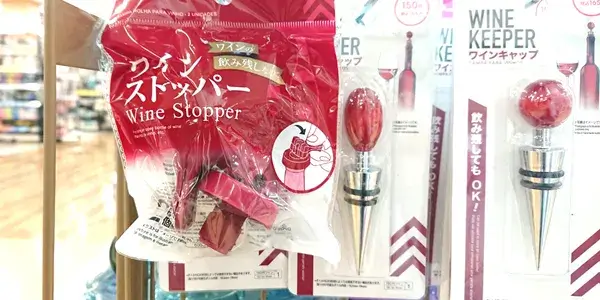 ダイソーの店頭で販売されているワインストッパーの写真。赤いパッケージに入ったシリコン製ストッパーと、隣には金属製のワインキャップが並んでいる。実際に確認した100均商品の一例