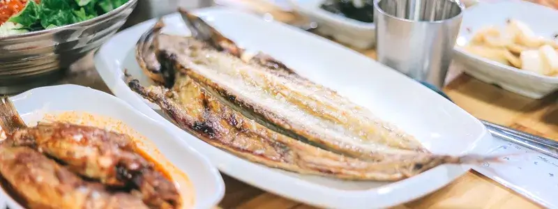 焼き上がったサバの干物が食卓に並んでいる様子。ワインと合わせて楽しむペアリングシーンをイメージさせる