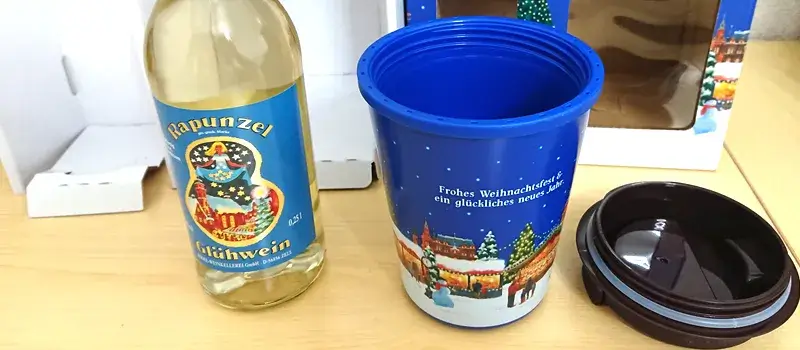 カルディの2025年グリューワインセットを自宅で開封し、白ワインボトルとオリジナルタンブラー、付属のフタを並べた様子