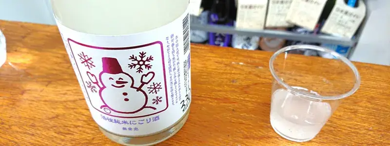 福屋尾崎商店の角打ちで提供されたにごり酒をグラスで楽しむ様子