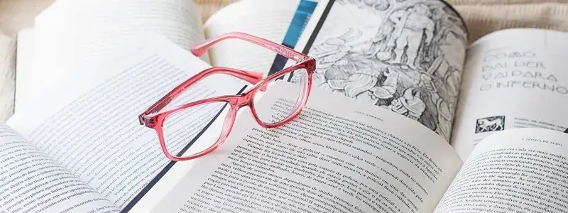 開いた本の上に置かれたピンクの眼鏡とワインに関する論文を示すイメージ