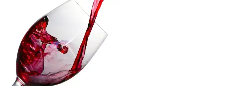 赤ワインが注がれる瞬間を捉えたグラスの写真。香りと余韻をイメージさせる動きのあるワインの流れ