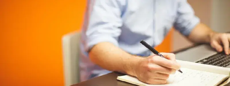 ノートにメモを取りながらパソコンで査定情報を確認する男性の写真。ロマネコンティの買取相場を調べているイメージ