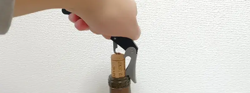 ソムリエナイフのてこ部分をボトル口にかけてコルクを引き抜く使い方の様子