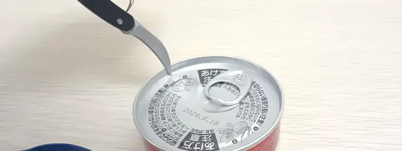 ソムリエナイフのナイフ部分で缶詰を開けようとしているが不安定な様子