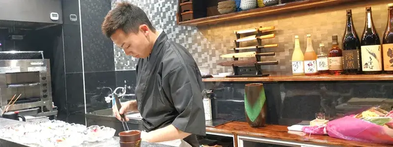 四代目魚盛の店主がカウンターで調理する様子。目の前で仕上げる割烹の臨場感